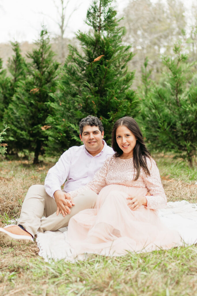 A cozy tree farm family photography session in Georgia, featuring a family posing among lush evergreens during golden hour.