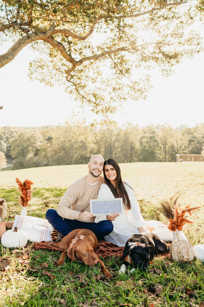 Caitlin and Kyle’s fall maternity session at a park in Flowery Branch, Georgia, featuring autumn foliage and a maternity picnic setup