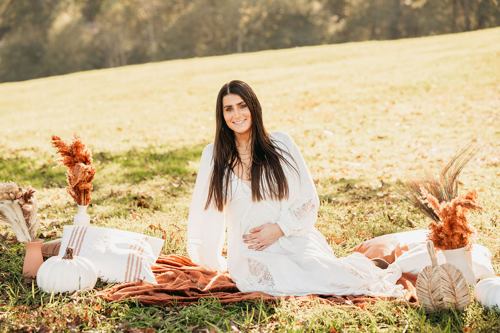 Caitlin and Kyle’s fall maternity session at a park in Flowery Branch, Georgia, featuring autumn foliage and a maternity picnic setup