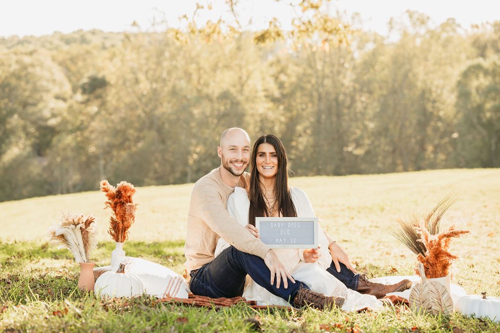Caitlin and Kyle’s fall maternity session at a park in Flowery Branch, Georgia, featuring autumn foliage and a maternity picnic setup