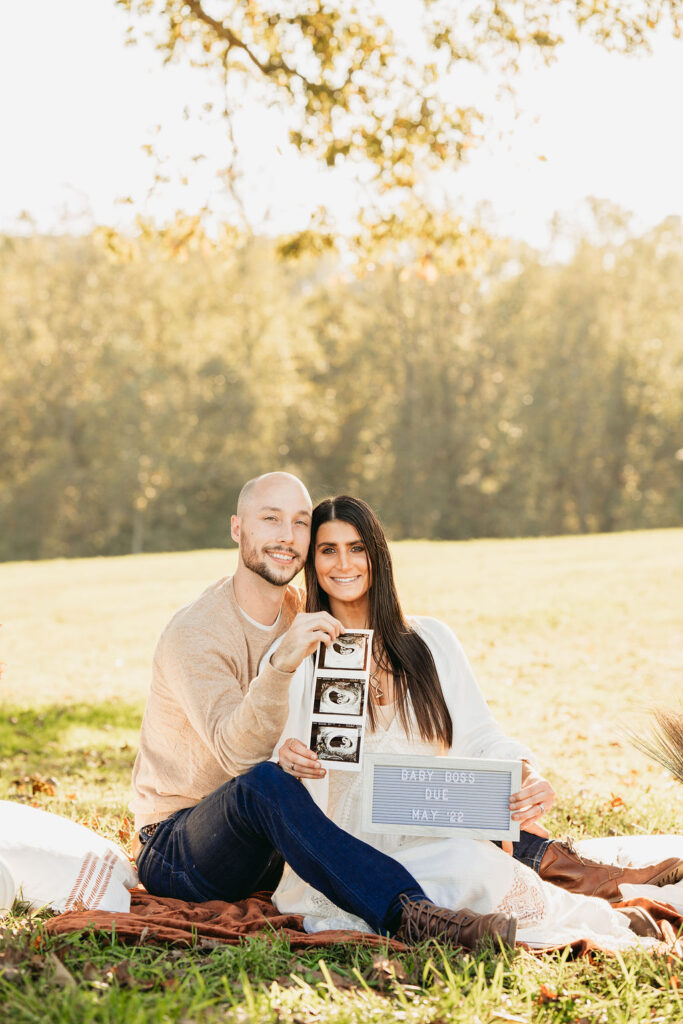 Caitlin and Kyle’s fall maternity session at a park in Flowery Branch, Georgia, featuring autumn foliage and a maternity picnic setup