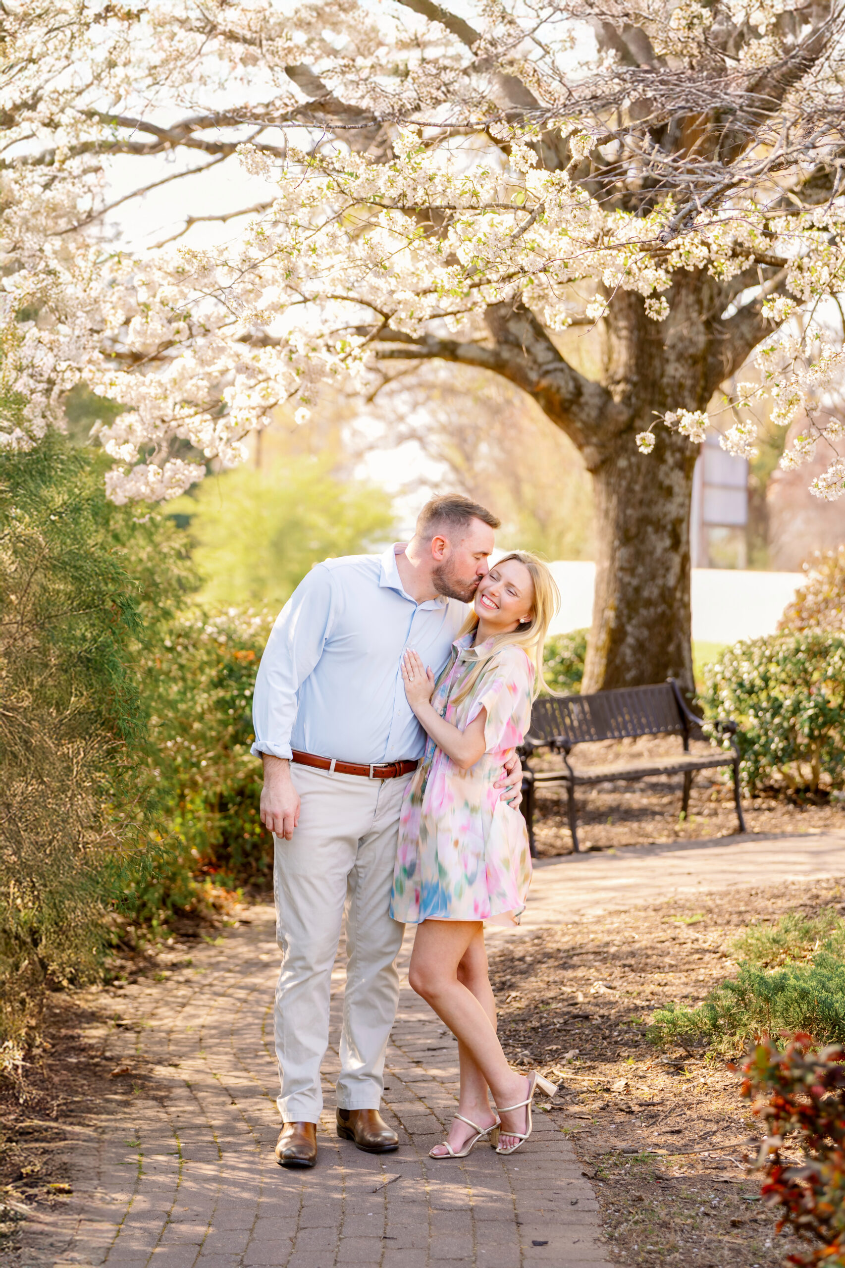 Newly engaged couple beneath white flowering trees