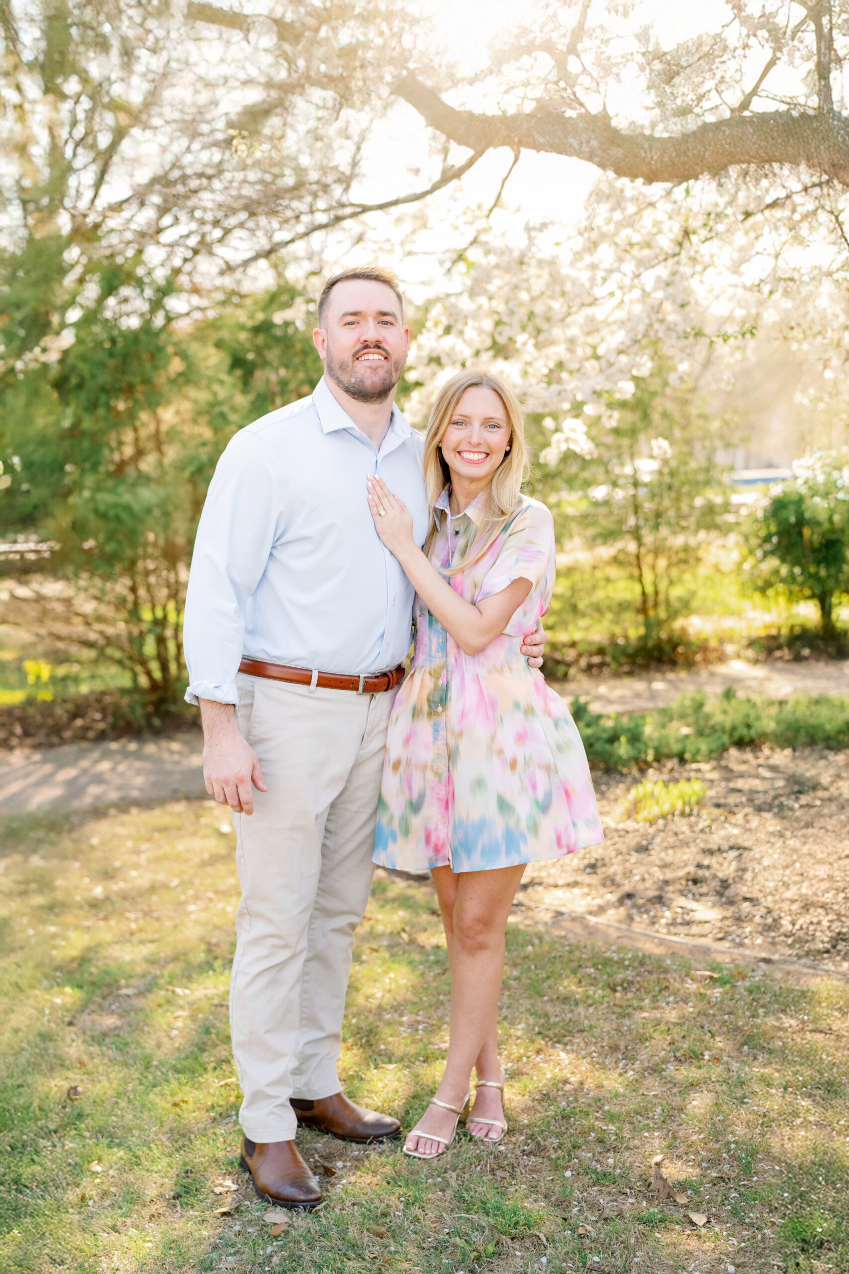 Newly engaged couple beneath white flowering trees